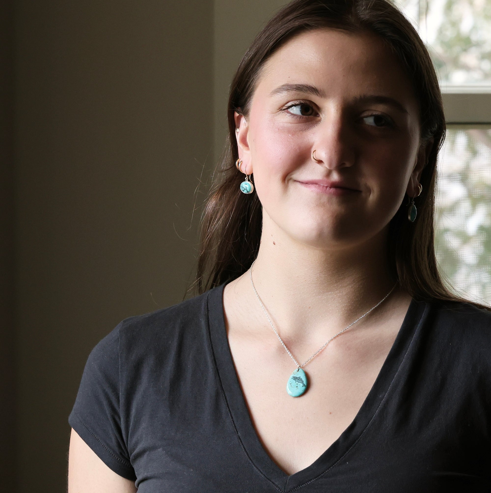 Woman wearing a necklace with a turquoise pendant indoors