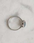 Silver ring with a blue gemstone on a marble surface