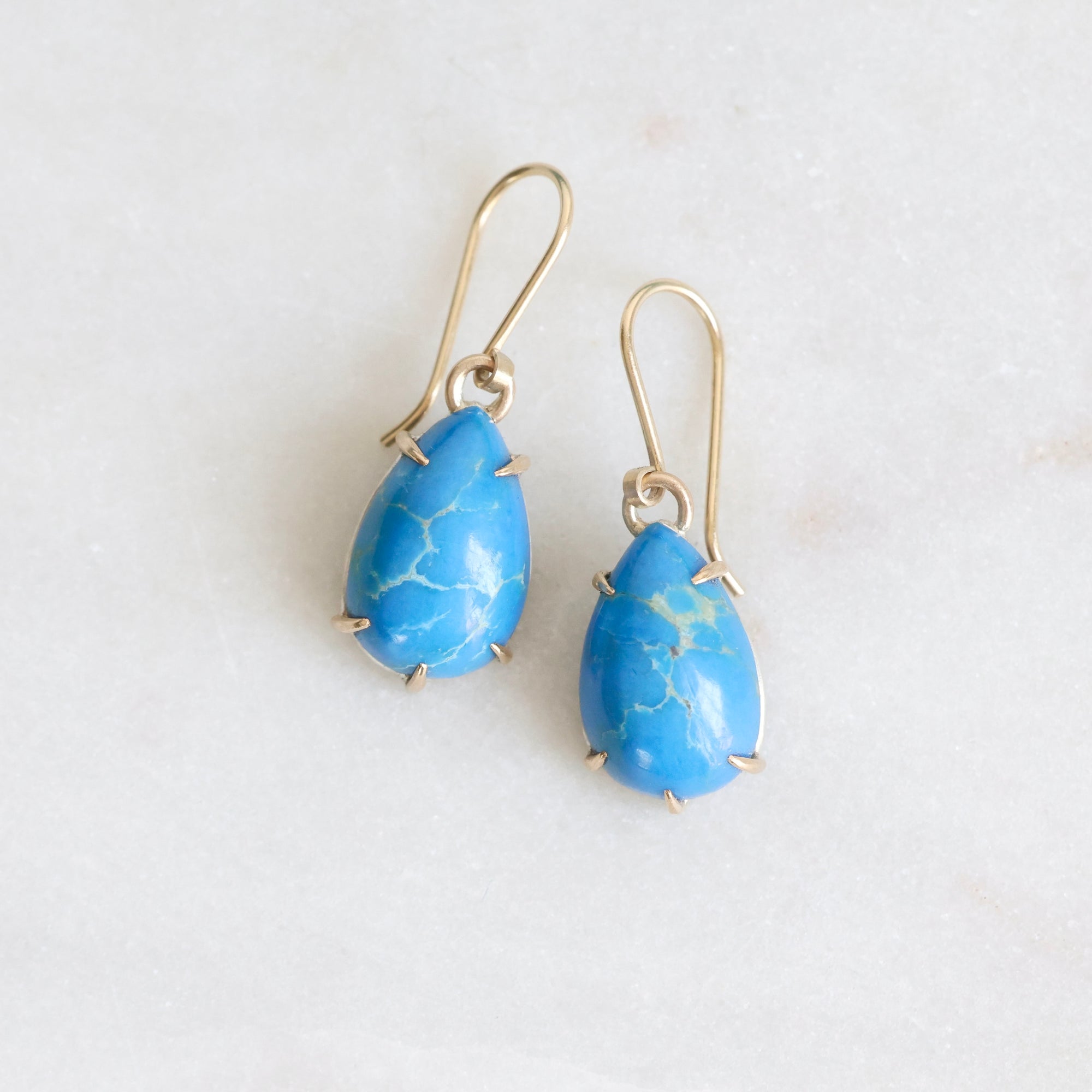 Pair of blue teardrop earrings on a white background
