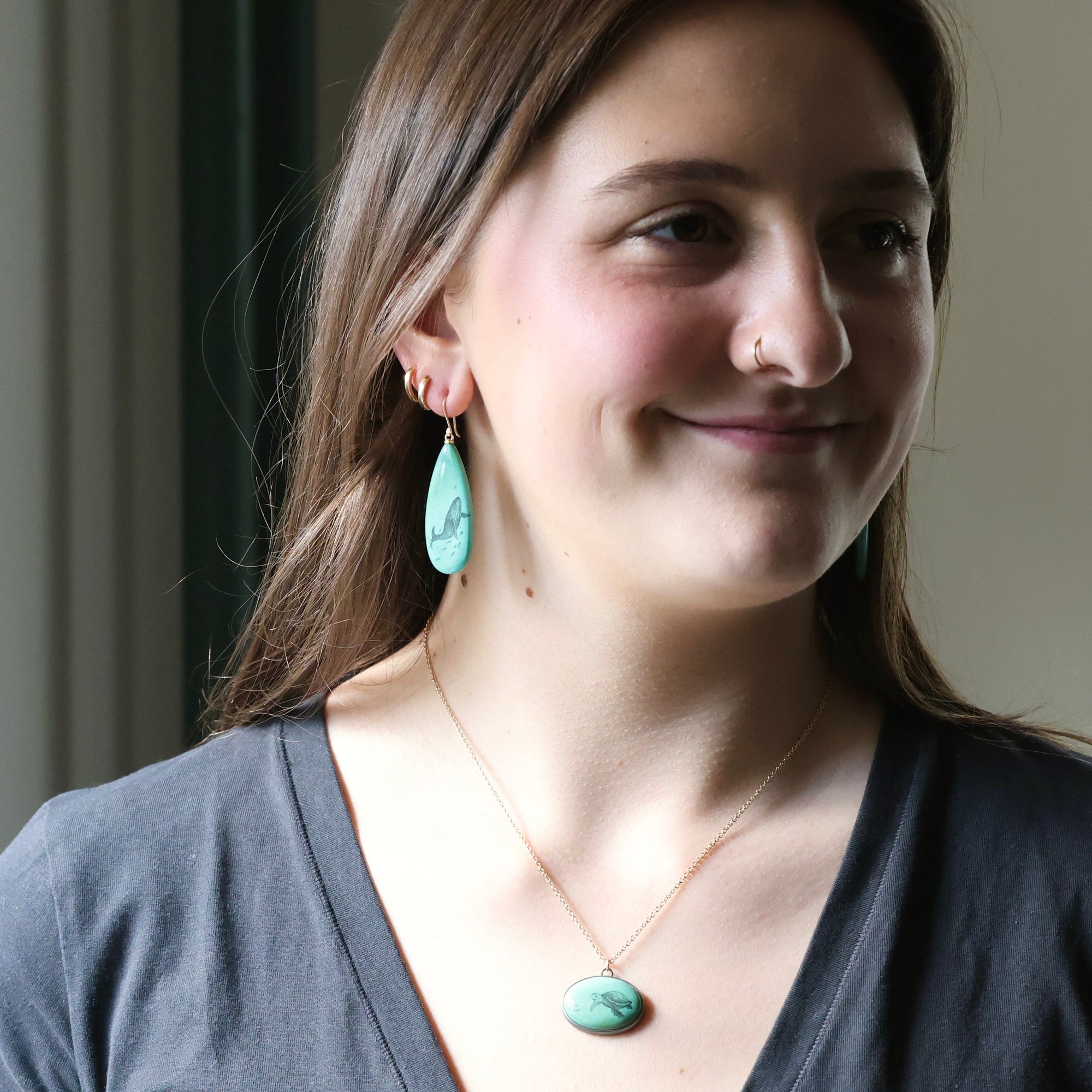 Woman wearing turquoise earrings and a necklace with a neutral background