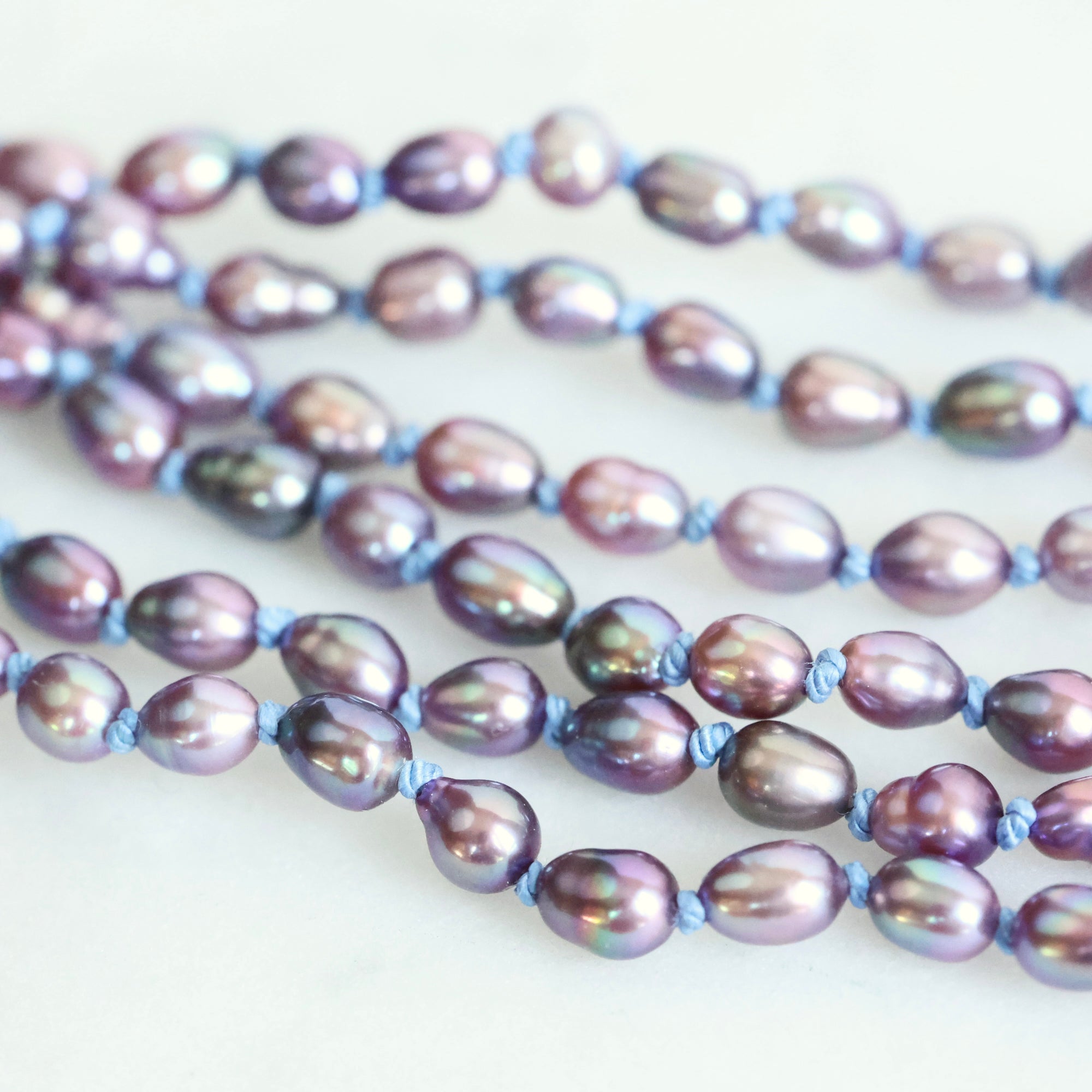 Two strands of purple and gray pearls on a white background