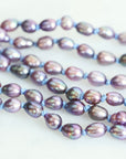 Two strands of purple and gray pearls on a white background