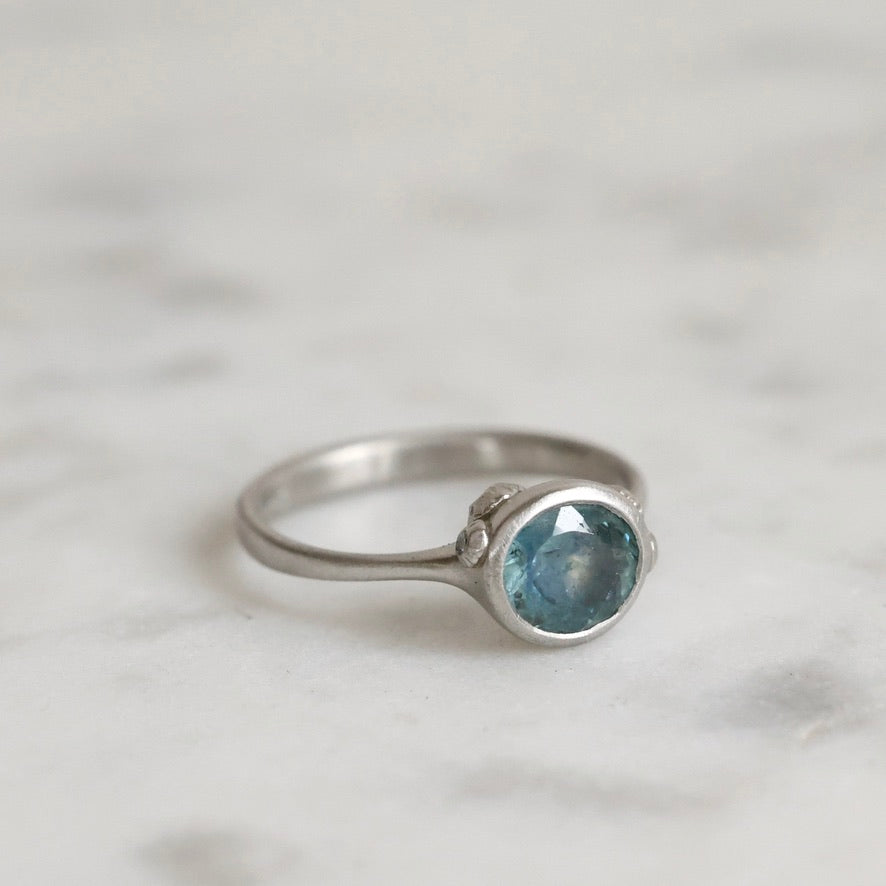 Silver ring with a blue gemstone on a light gray background