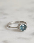 Silver ring with a blue gemstone on a light gray background