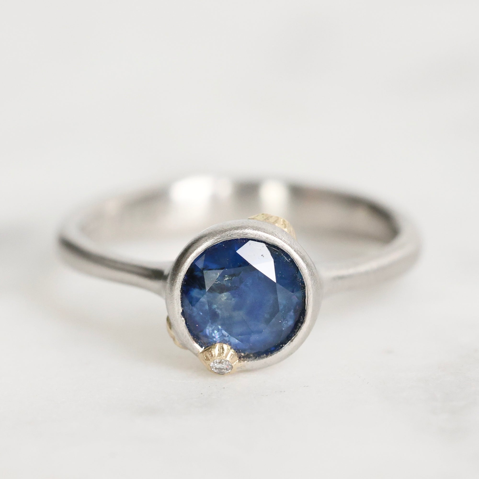 Silver ring with a blue gemstone on a light gray background