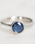 Silver ring with a blue gemstone on a light gray background