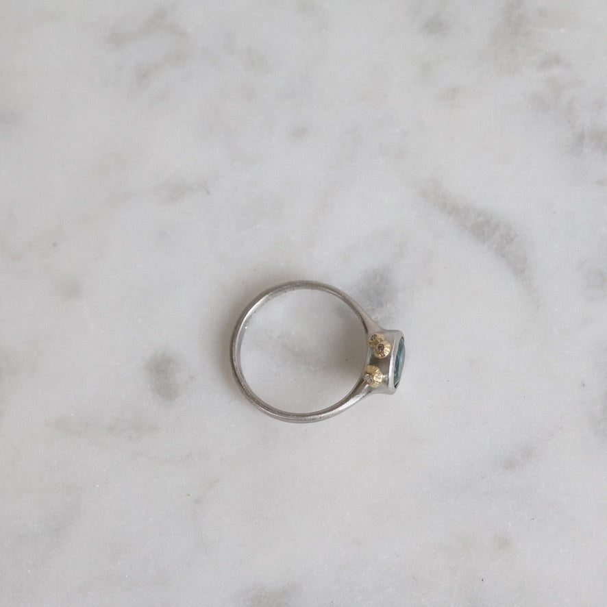 Silver ring with a small diamond on a marble surface