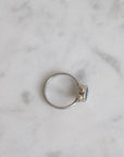 Silver ring with a small diamond on a marble surface