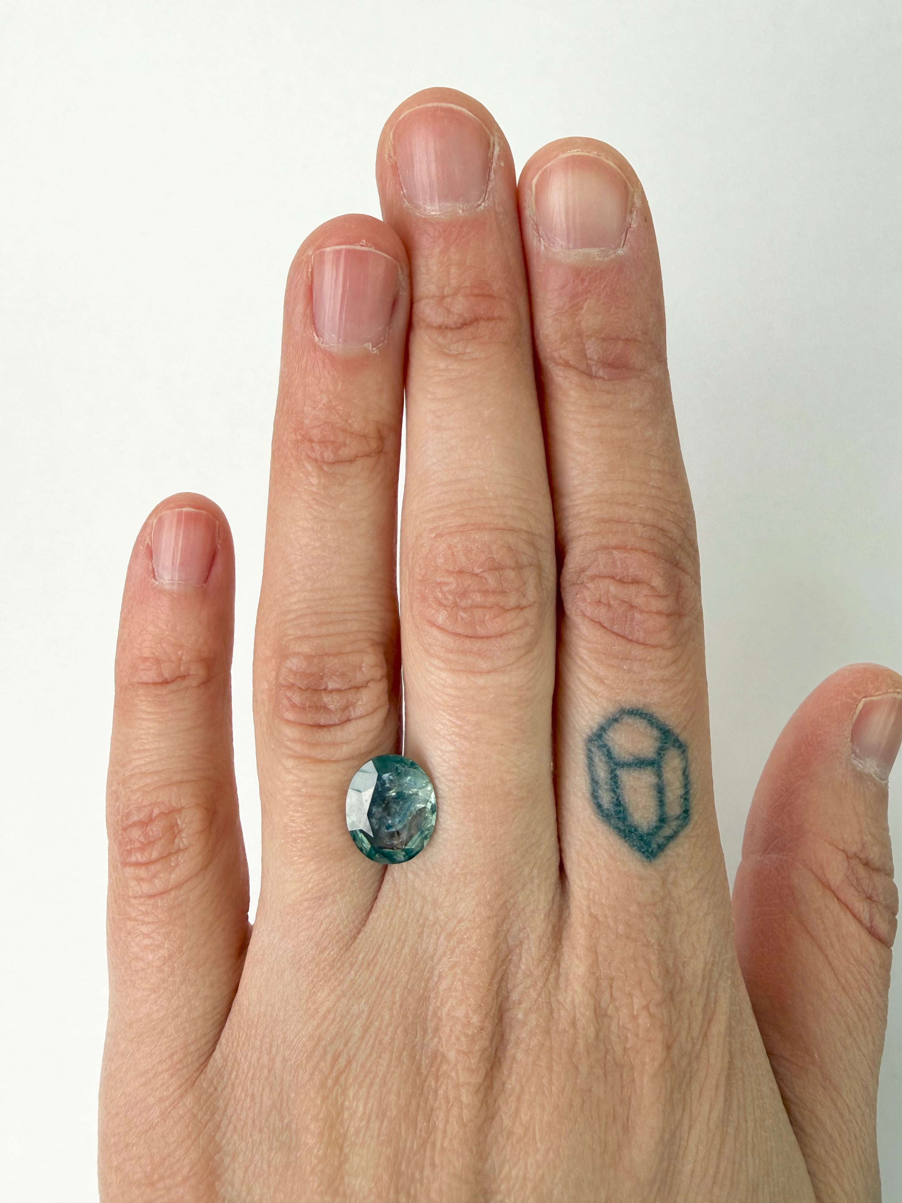Hand with a ring featuring a green gemstone on a white background