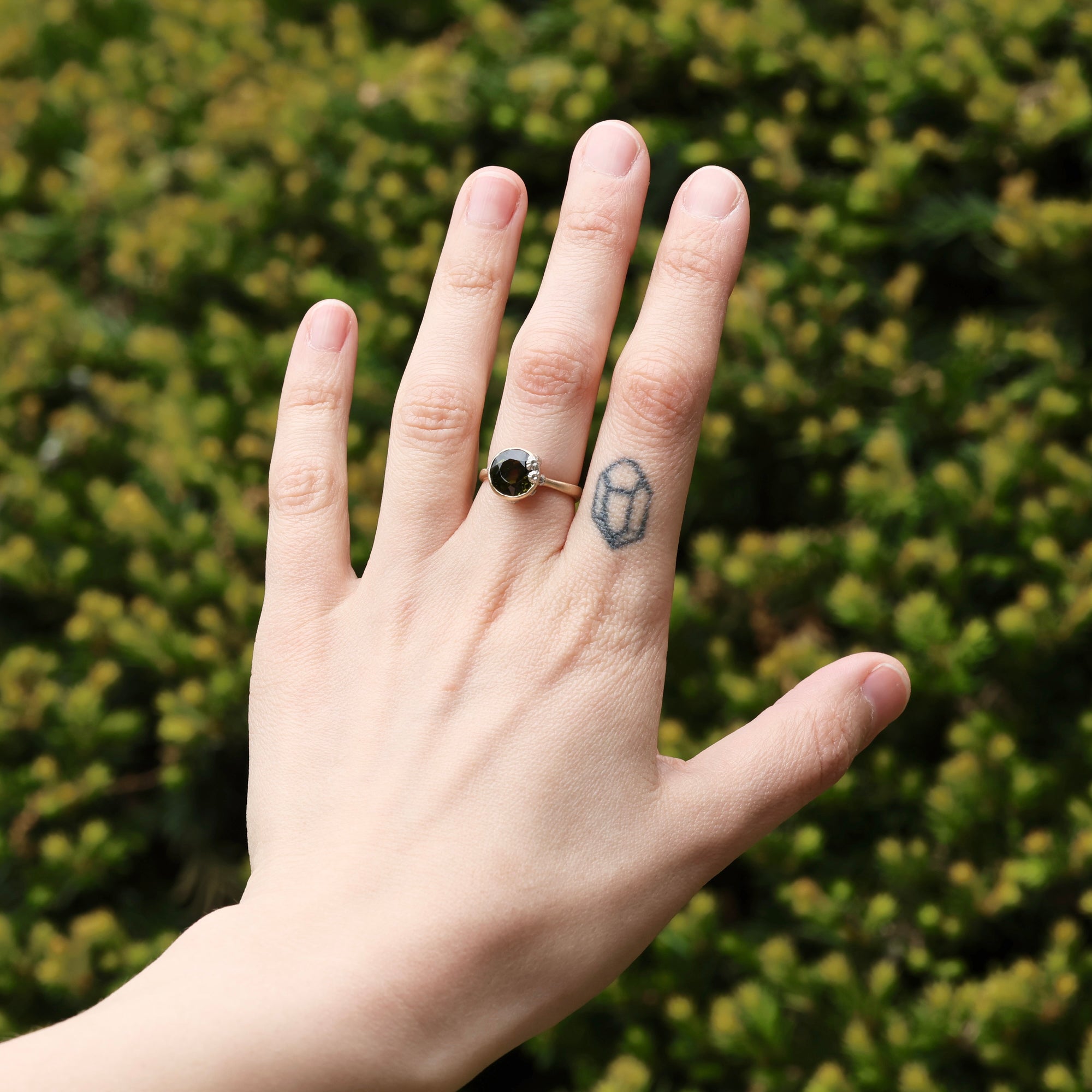 green gemstone ring with barnacles on hand