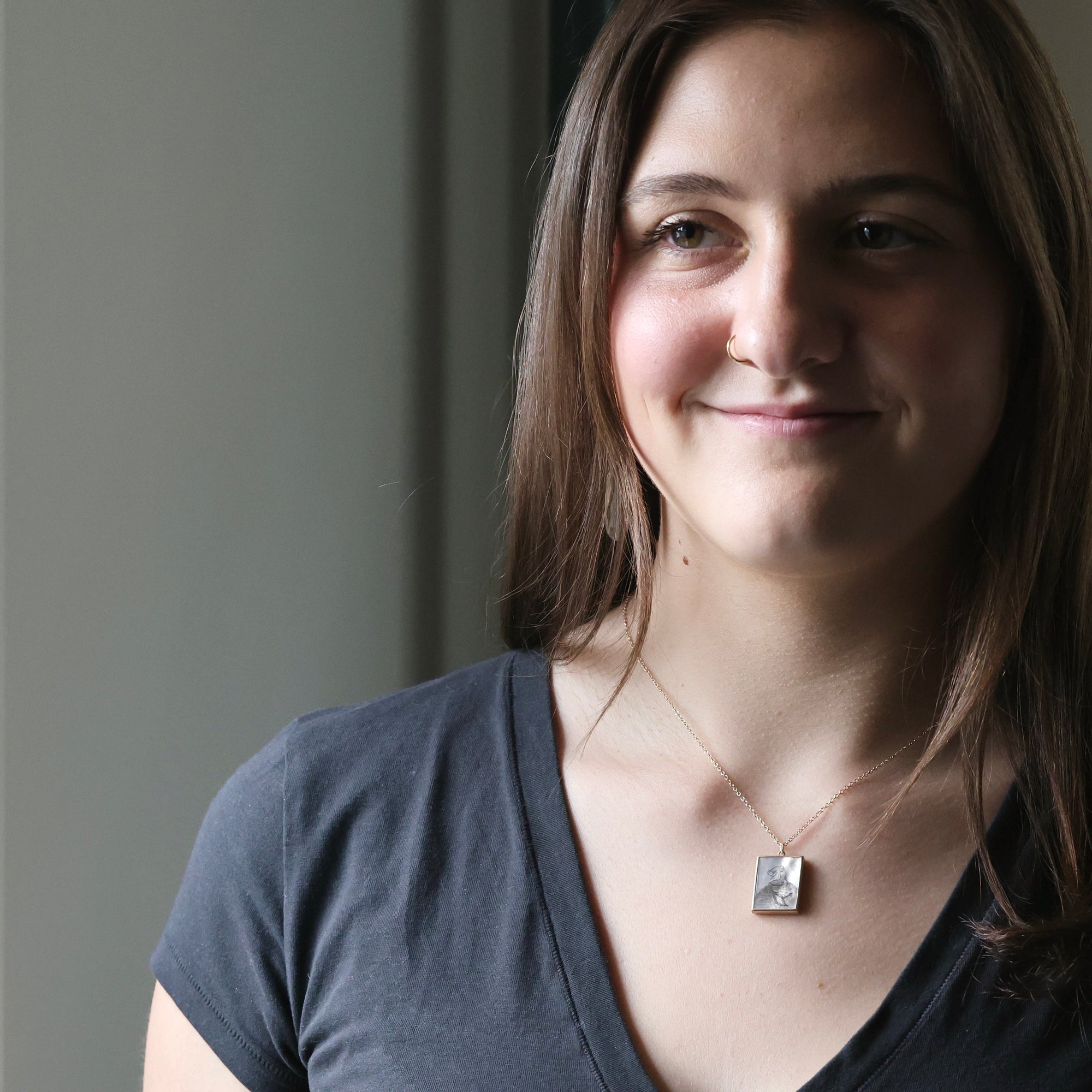 Woman wearing a necklace with a pendant against a neutral background