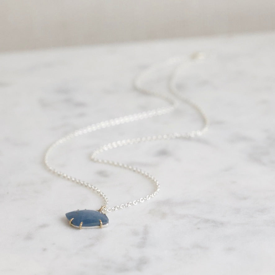 Necklace with a blue pendant on a marble surface