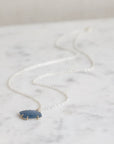 Necklace with a blue pendant on a marble surface