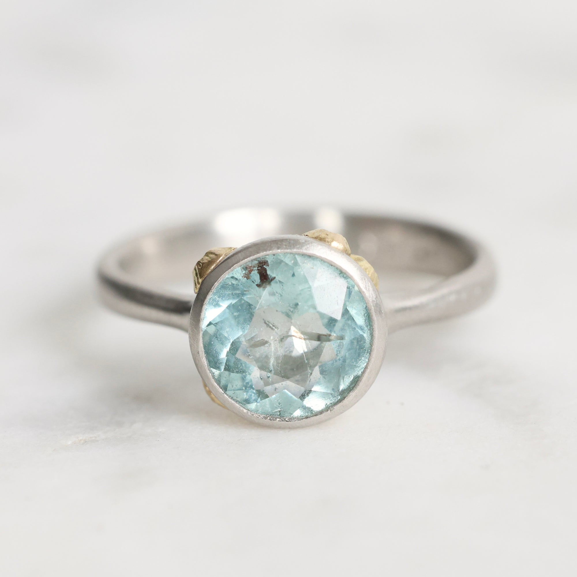 Silver ring with a blue gemstone on a light gray background