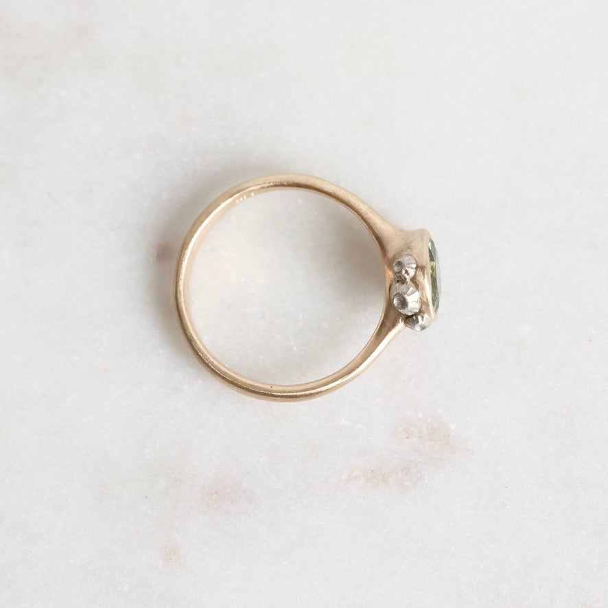 Gold ring with a small barnacles on a light marble background