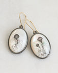 Oval-shaped earrings with jellyfish illustrations on a light background