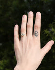 Hand with a diamond ring on a finger and a small tattoo, against a blurred green background