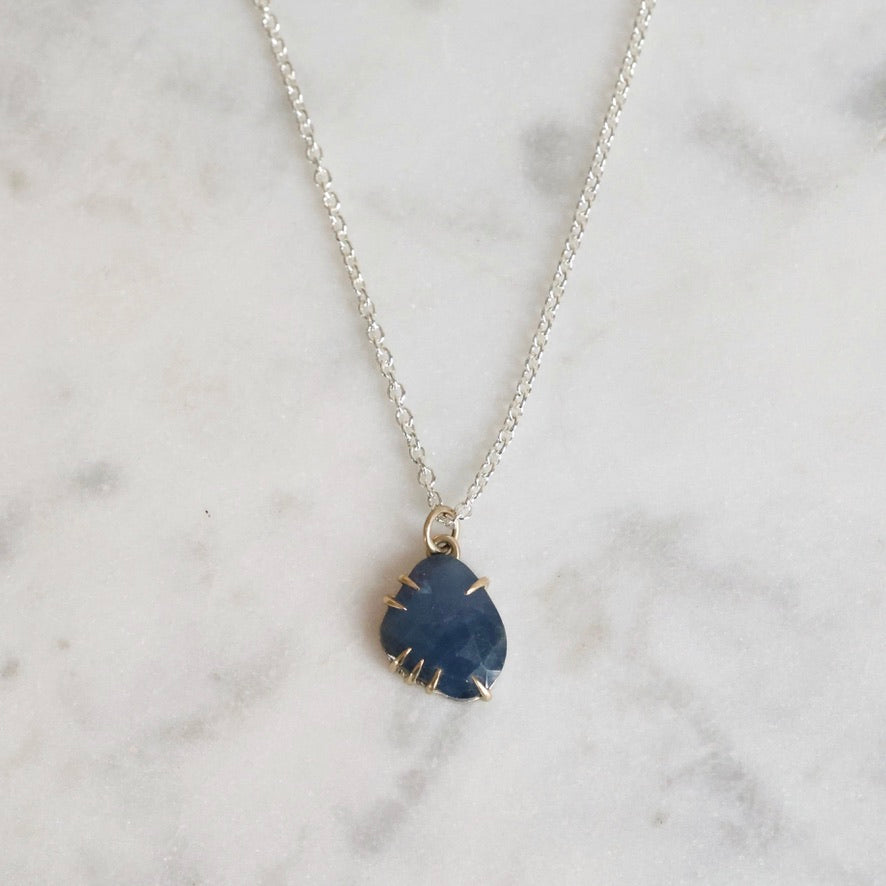Necklace with a blue pendant on a marble surface