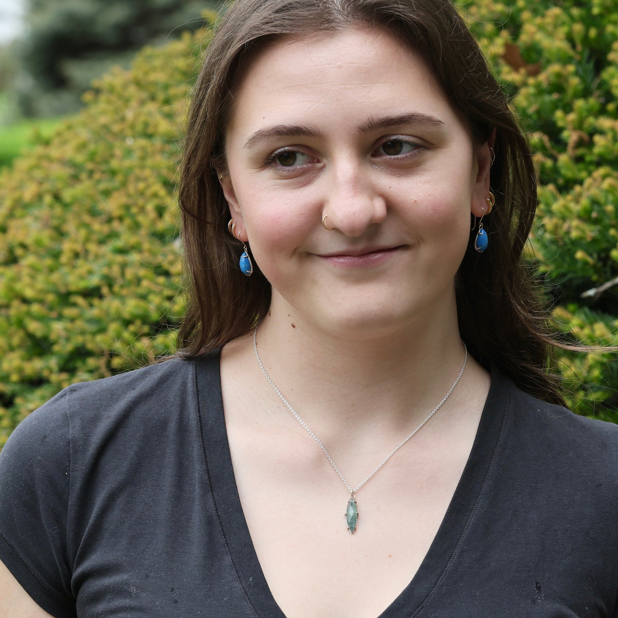 Woman wearing necklace with sharp blue/green gemstone