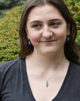Woman wearing necklace with sharp blue/green gemstone