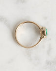 Gold ring with a green gemstone on a marble surface
