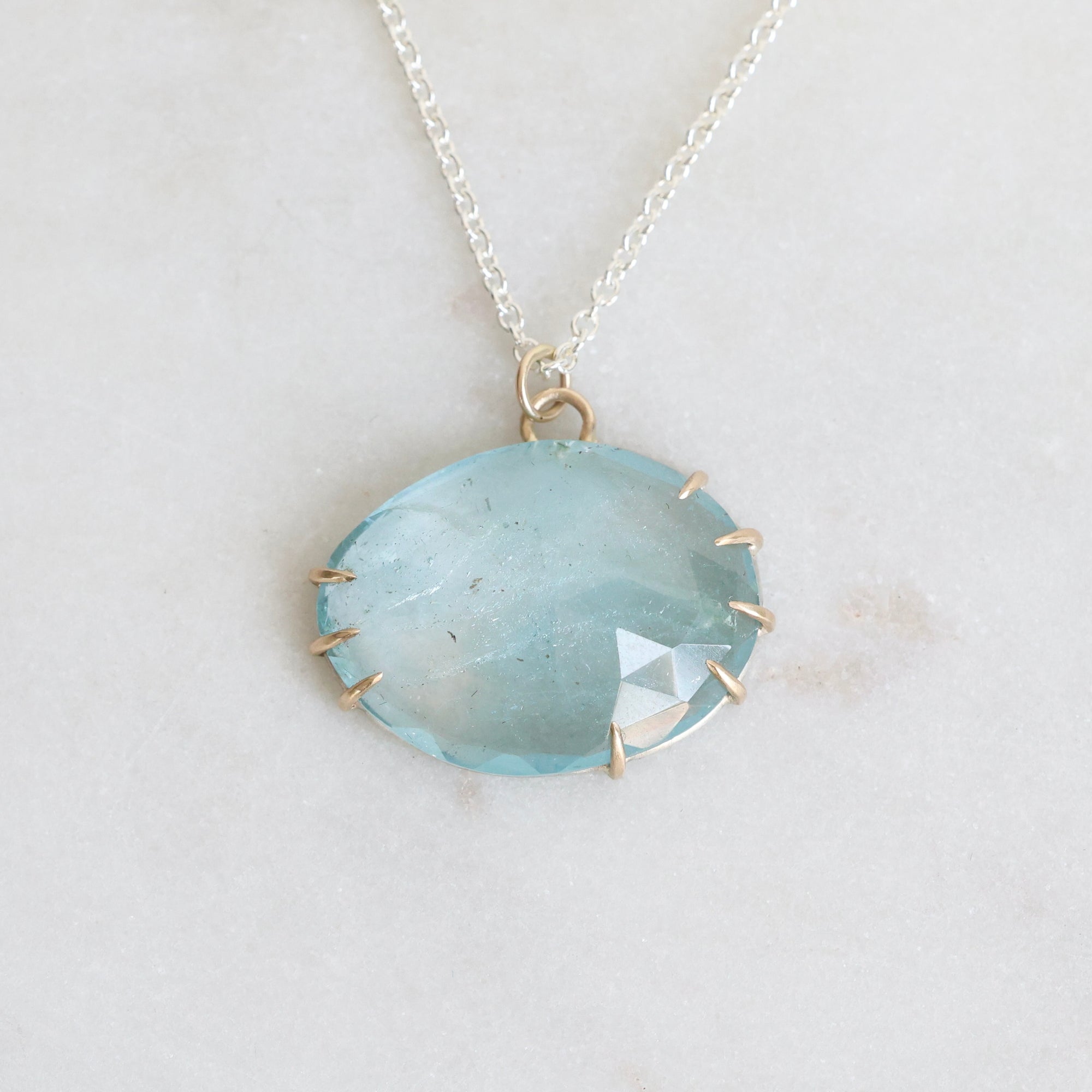 Necklace with a large round blue stone pendant on a light gray background