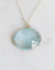 Necklace with a large round blue stone pendant on a light gray background