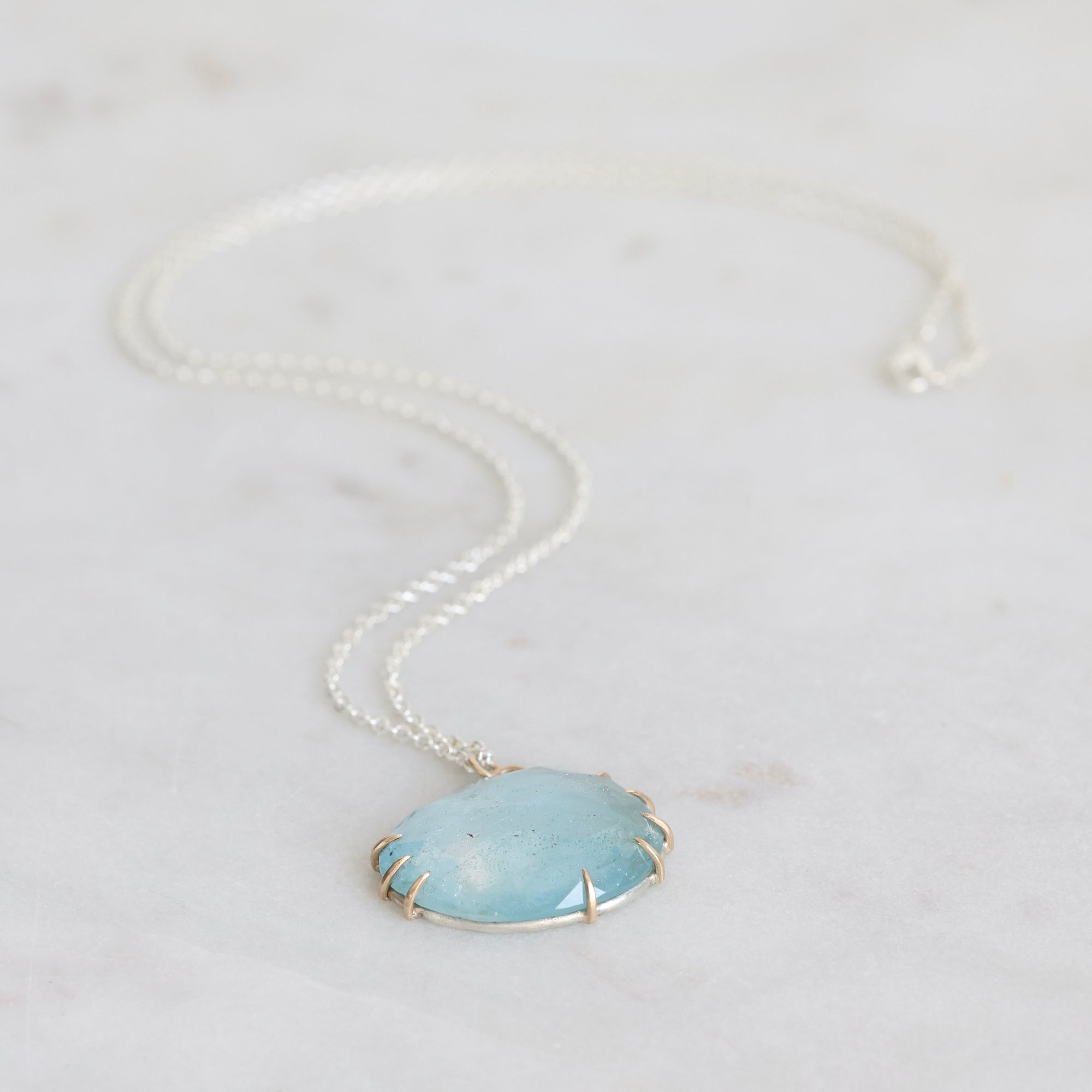 Necklace with a large round blue stone pendant on a light gray background