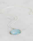 Necklace with a large round blue stone pendant on a light gray background