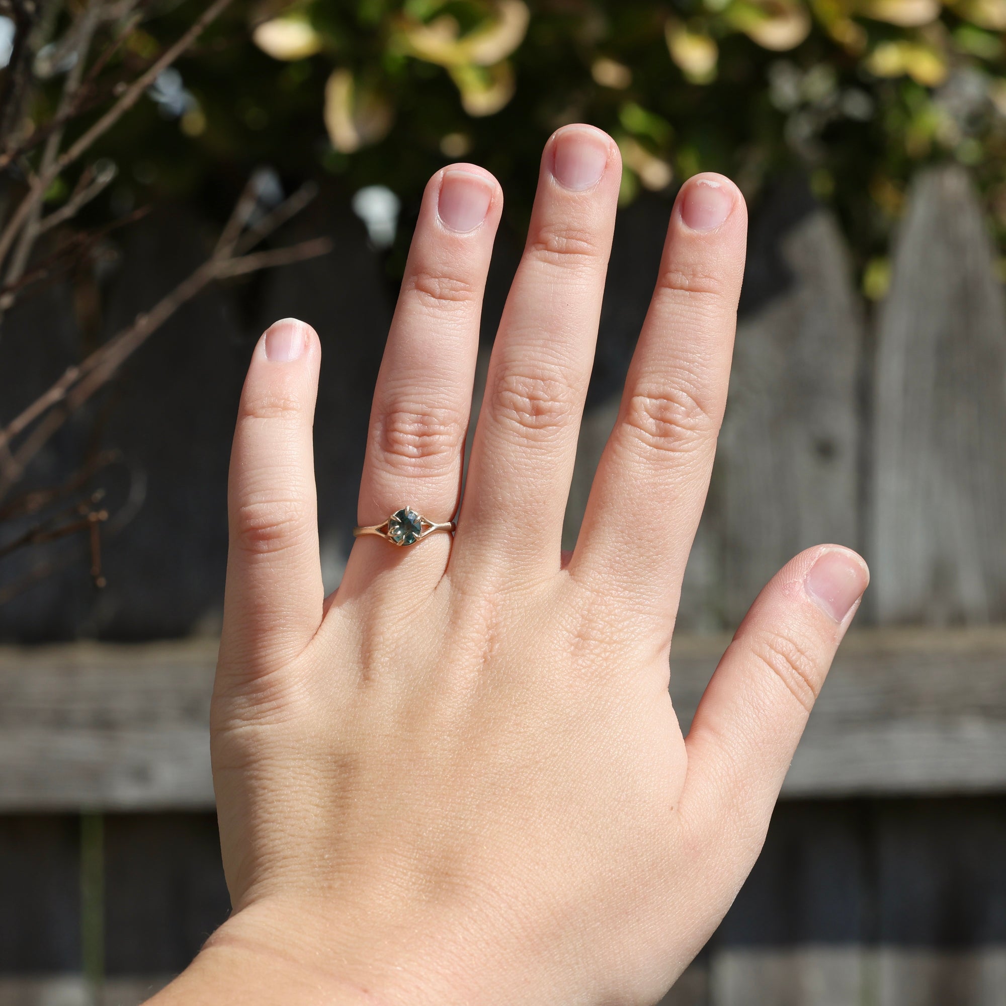 Green/blue sapphire in gold branchy setting on hand