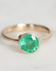 Gold ring with a green gemstone on a light gray background