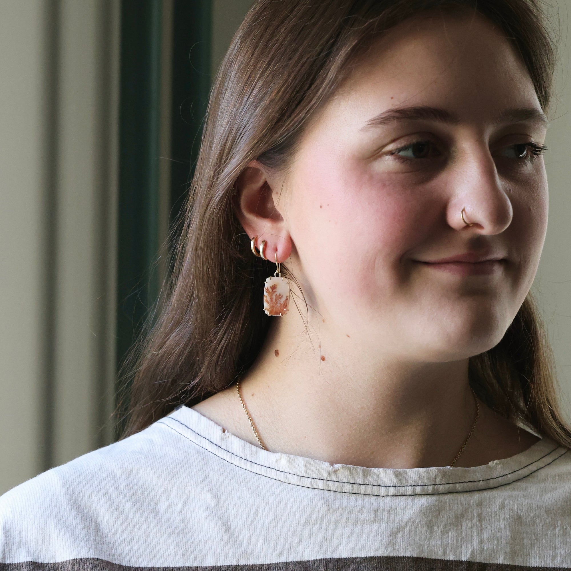 Close-up of a person wearing earrings with a neutral background