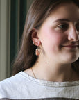 Close-up of a person wearing earrings with a neutral background