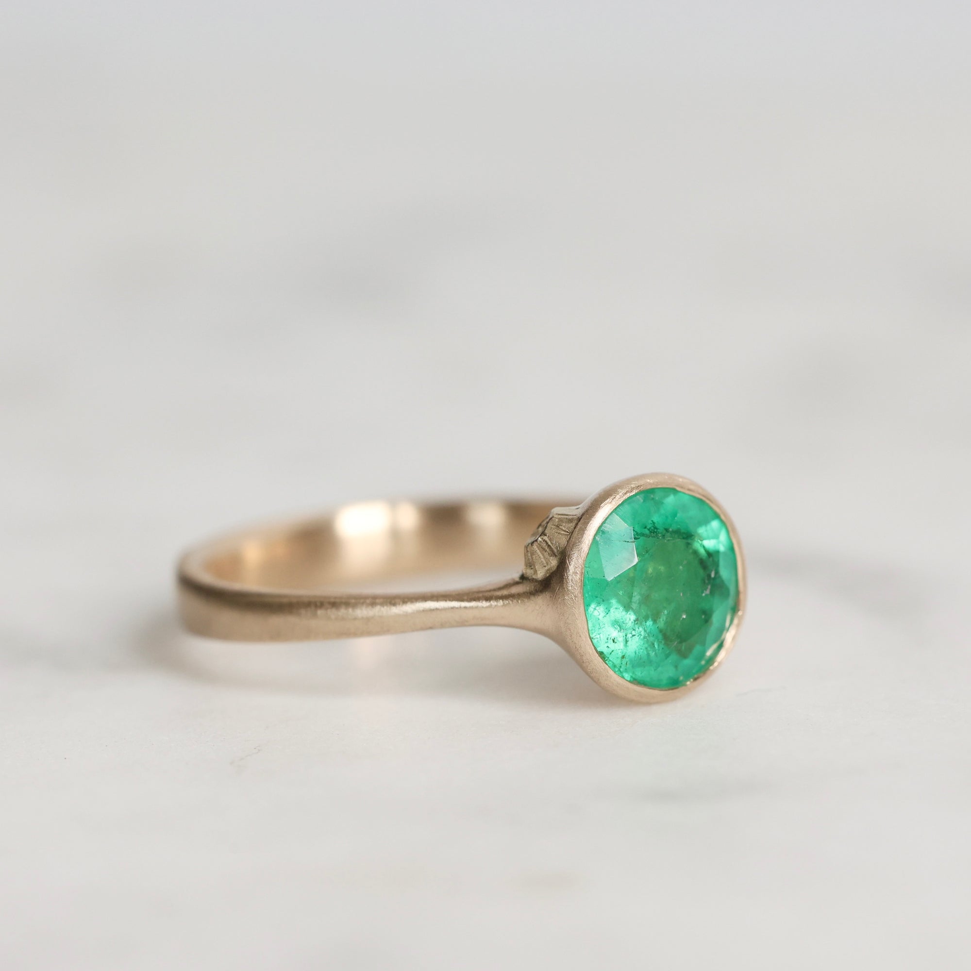 Silver ring with a green gemstone on a light gray background