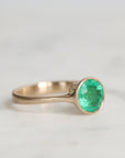 Silver ring with a green gemstone on a light gray background