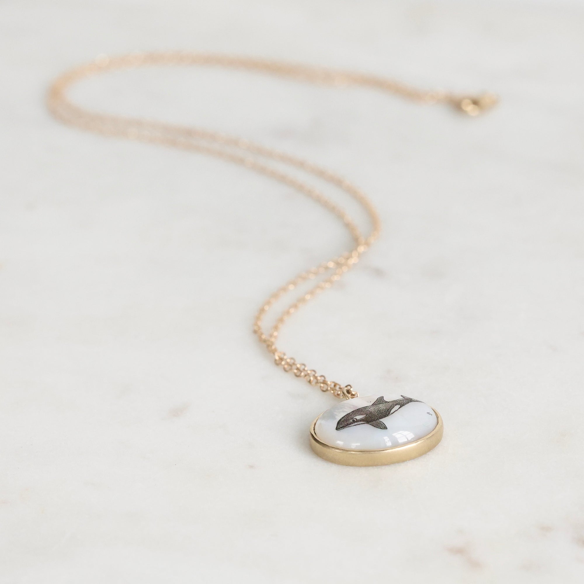 Necklace with a pendant featuring an orca on a light background