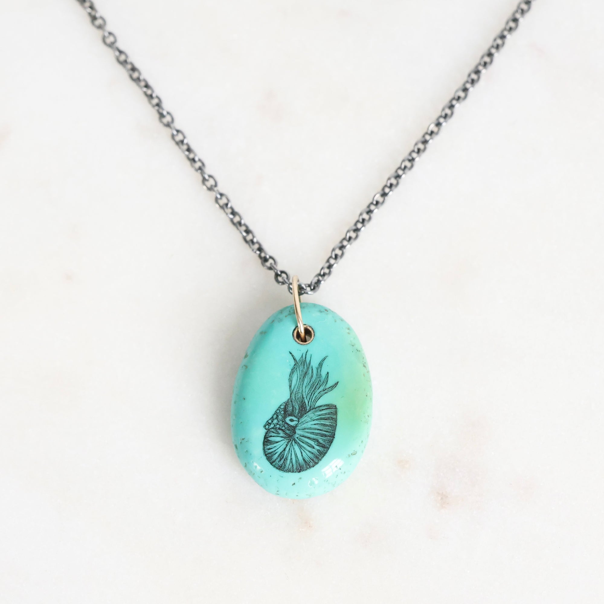 Necklace with a turquoise pendant featuring a black design on a white background