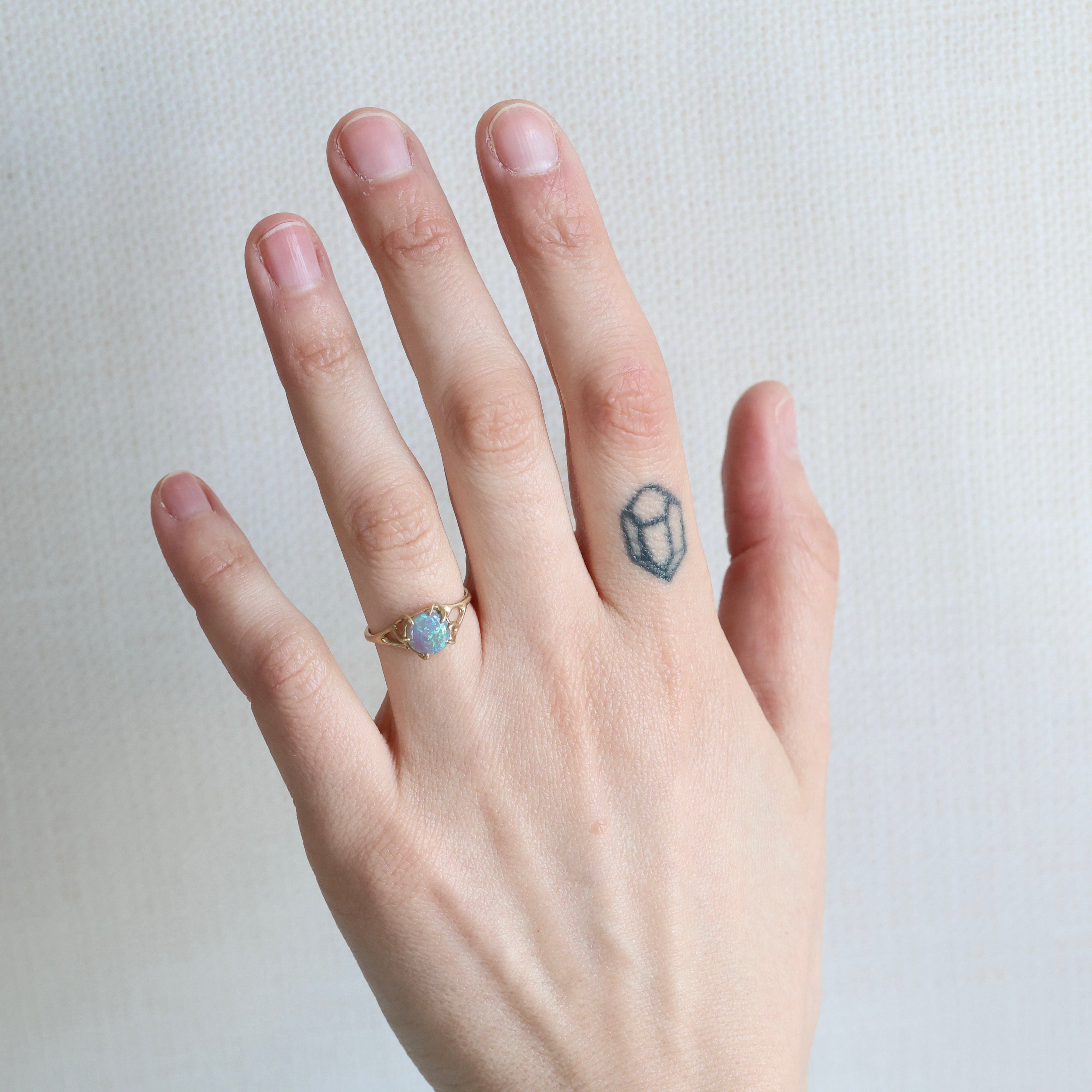 Hand with a ring and a small tattoo on a plain background
