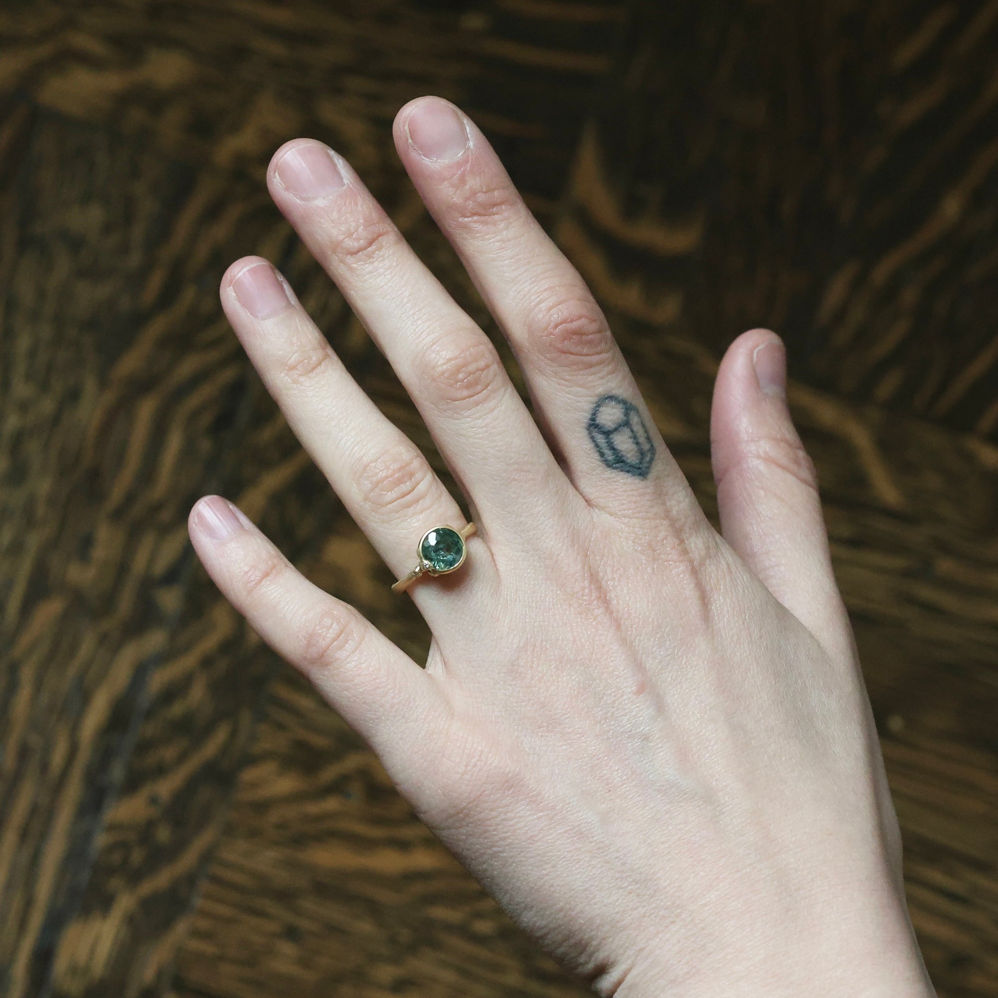 Hand with a ring and tattoo on a textured brown background