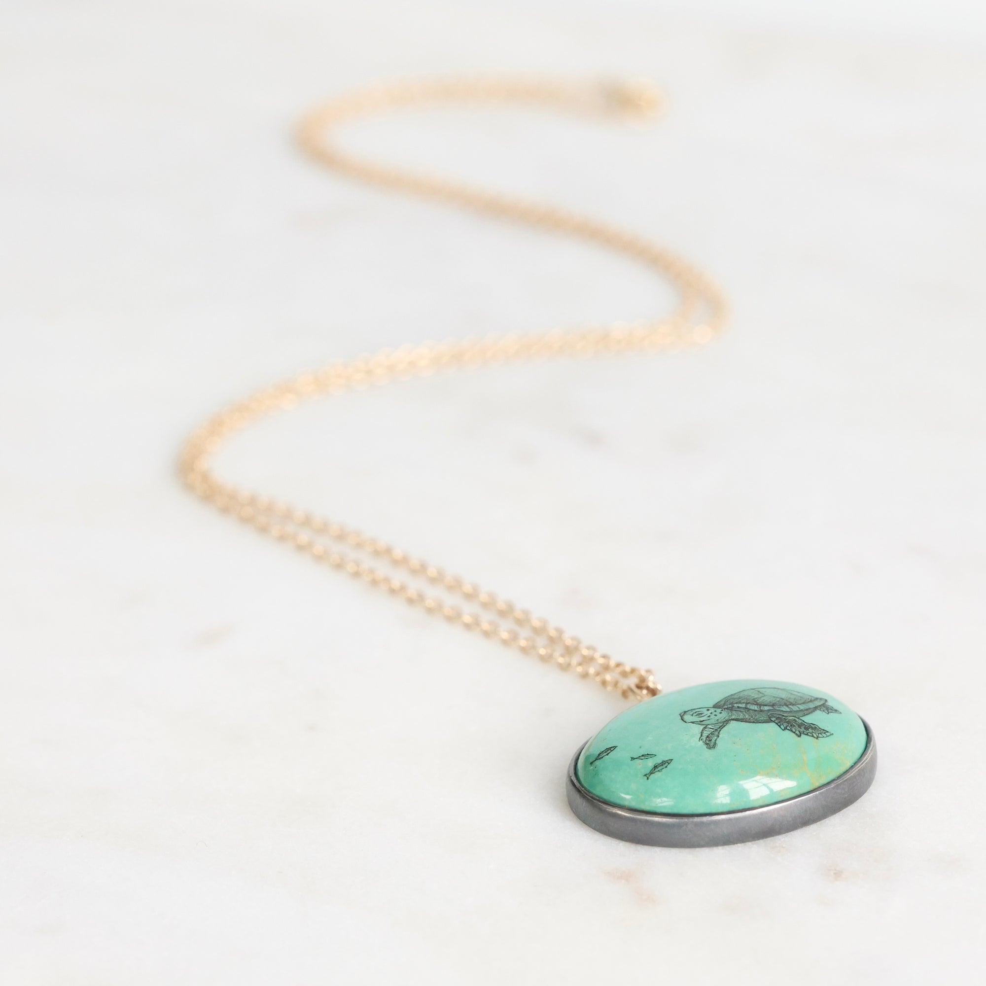 Necklace with a turquoise pendant featuring a turtle design on a white background