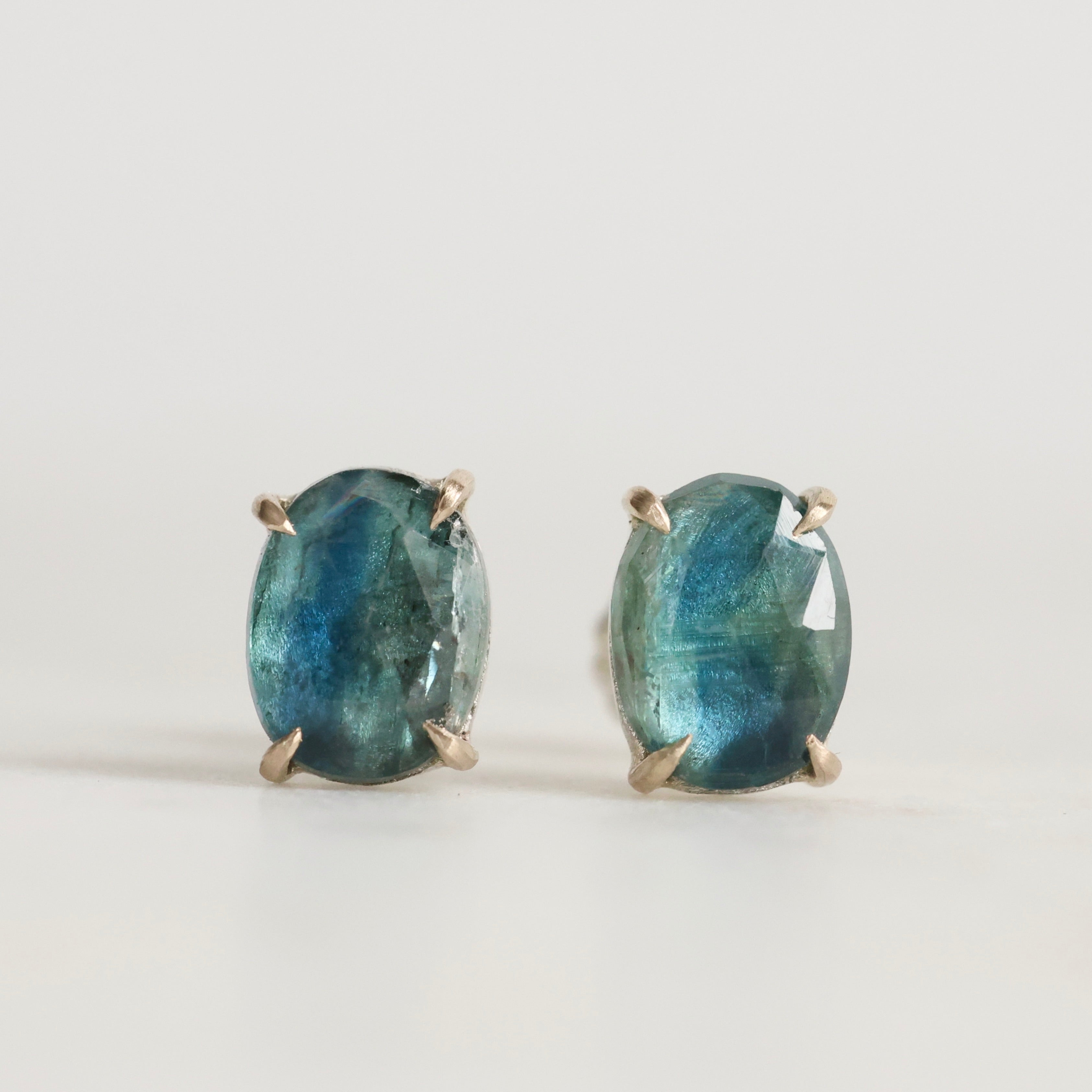 Pair of green gemstone earrings on a light gray background