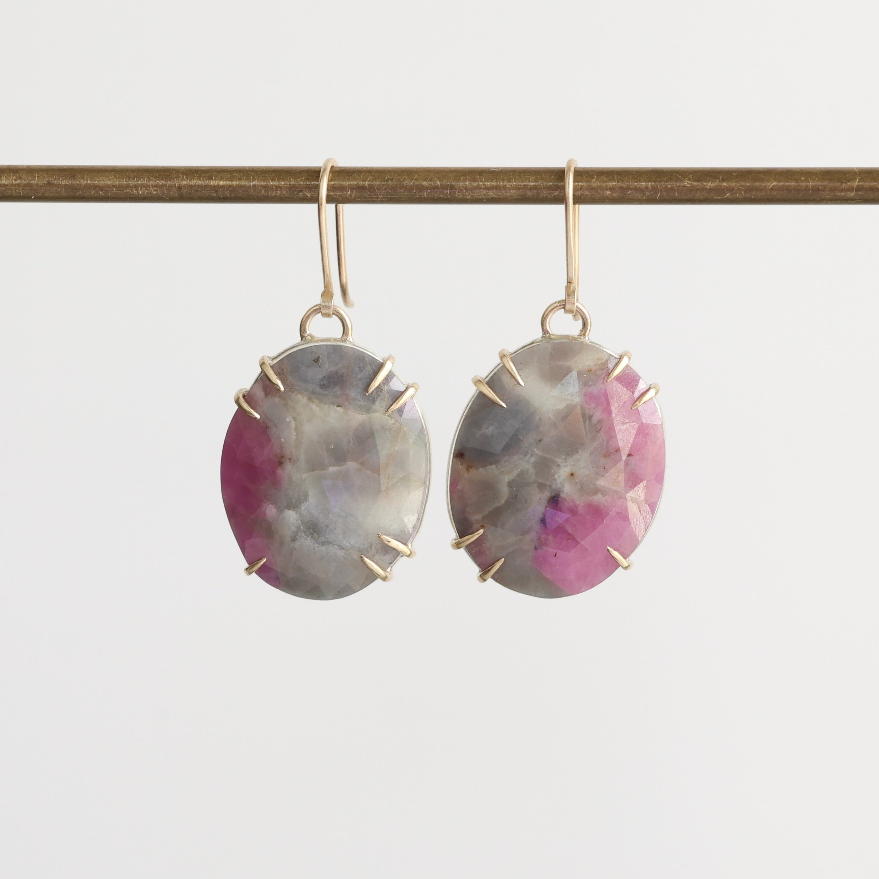 Pair of earrings with pink and gray stones on a white background