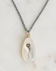 Teardrop-shaped pendant with jellyfish design on a chain against a marble background