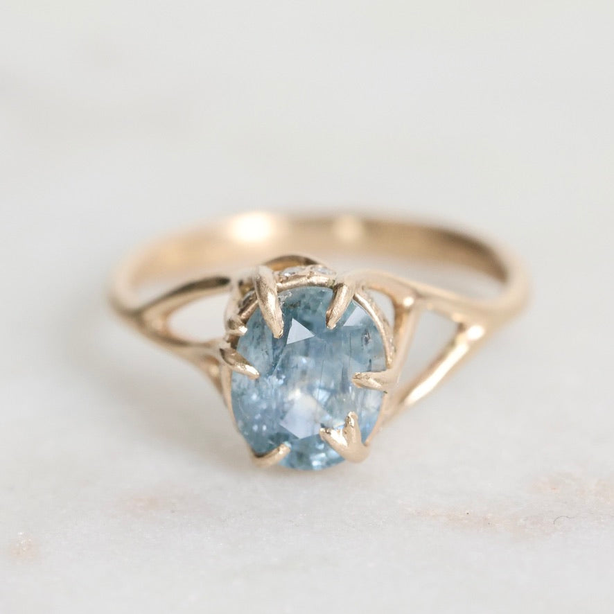 Gold ring with a blue gemstone on a light gray background