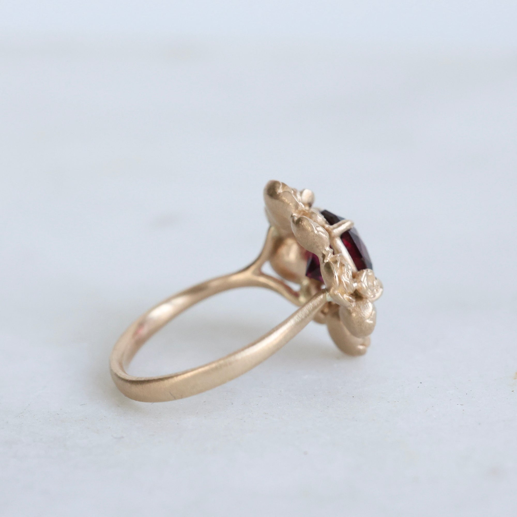 Gold ring with a red gemstone on a light gray background