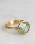 Gold ring with a green gemstone on a light background