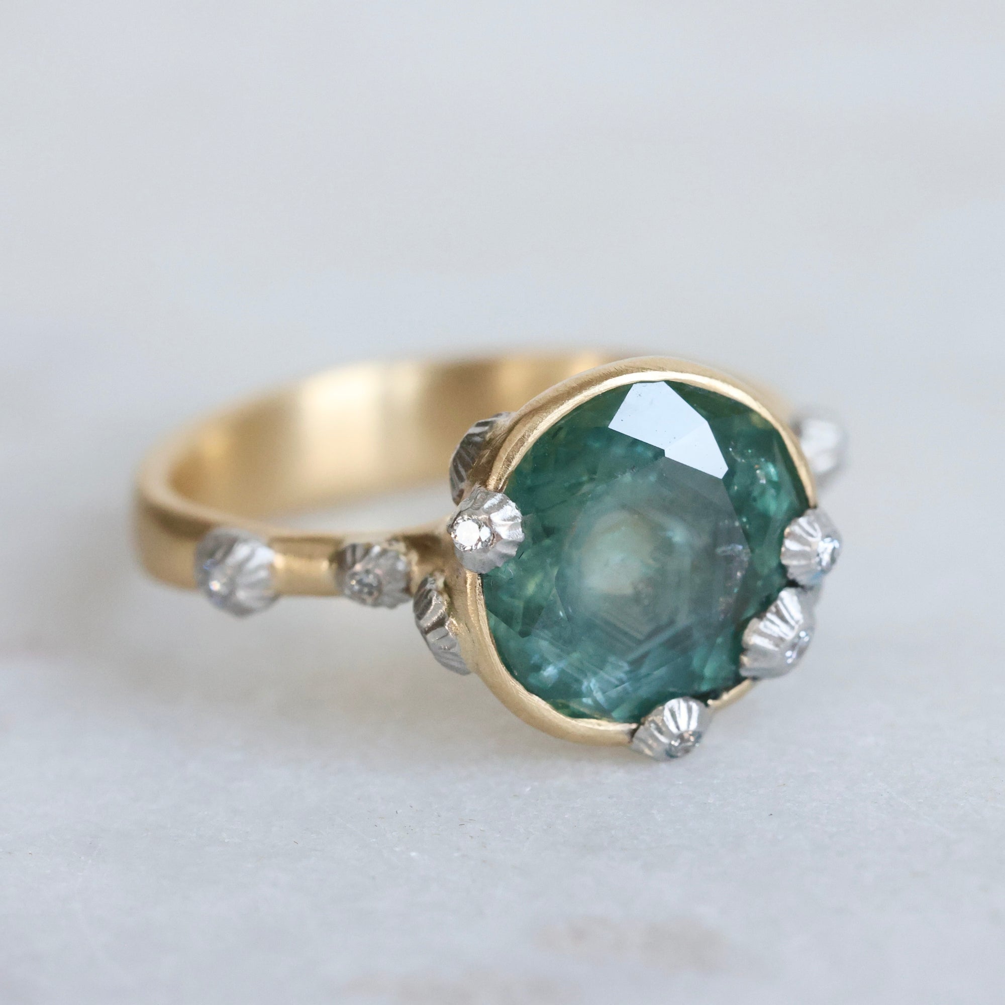 Large green sapphire ring with lots of barnacles. Gold shank. 