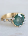 Large green sapphire ring with lots of barnacles. Gold shank. 