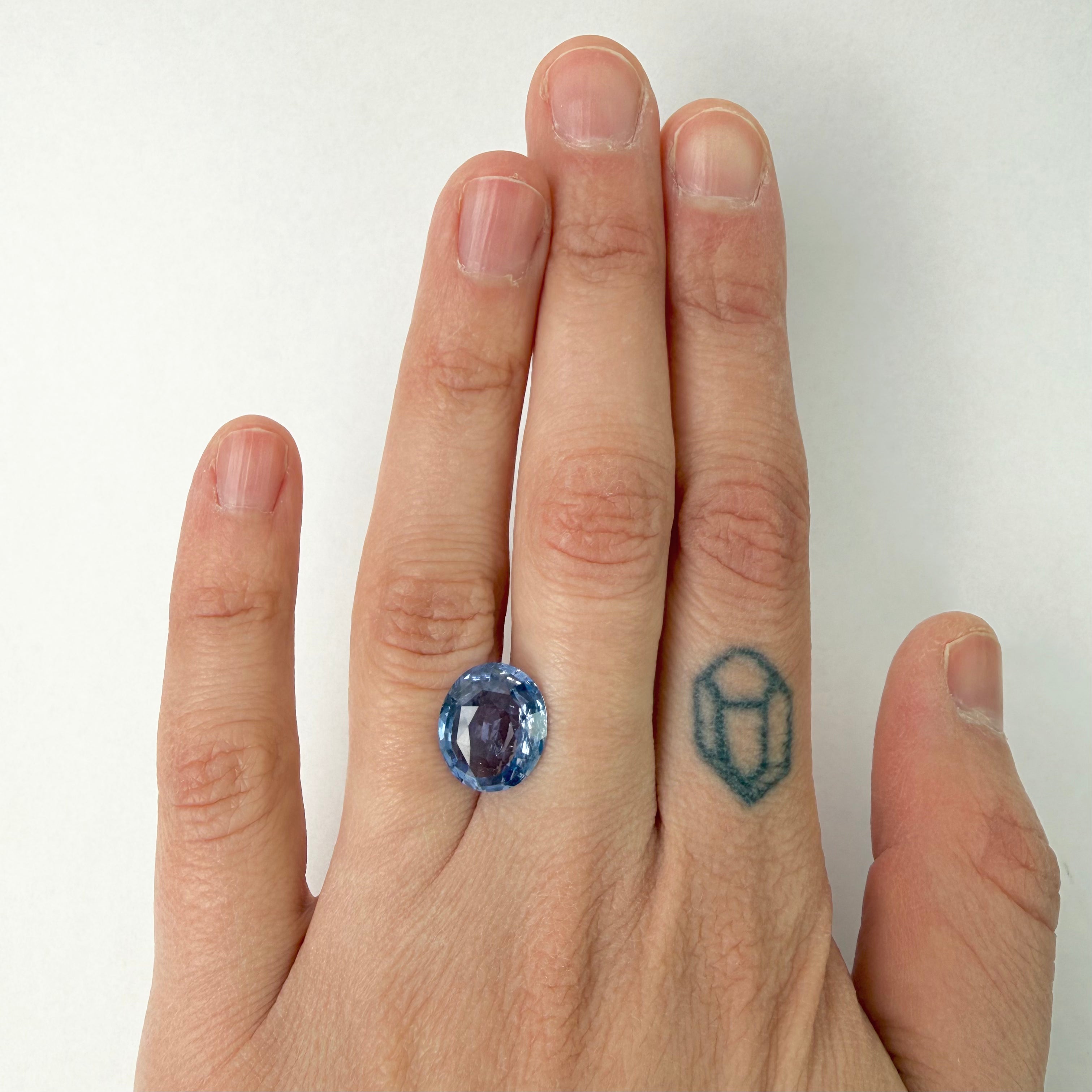 Hand wearing a blue gemstone on a white background