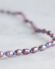 Pearl necklace with purple and pink beads on a light background